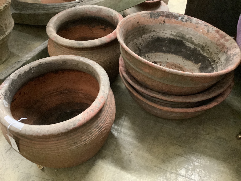 A pair of terracotta pots and three other terracotta pots, largest